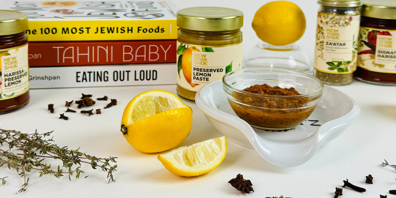 Spices, lemons, and a book titled '100 Most Jewish Foods' on a white surface.